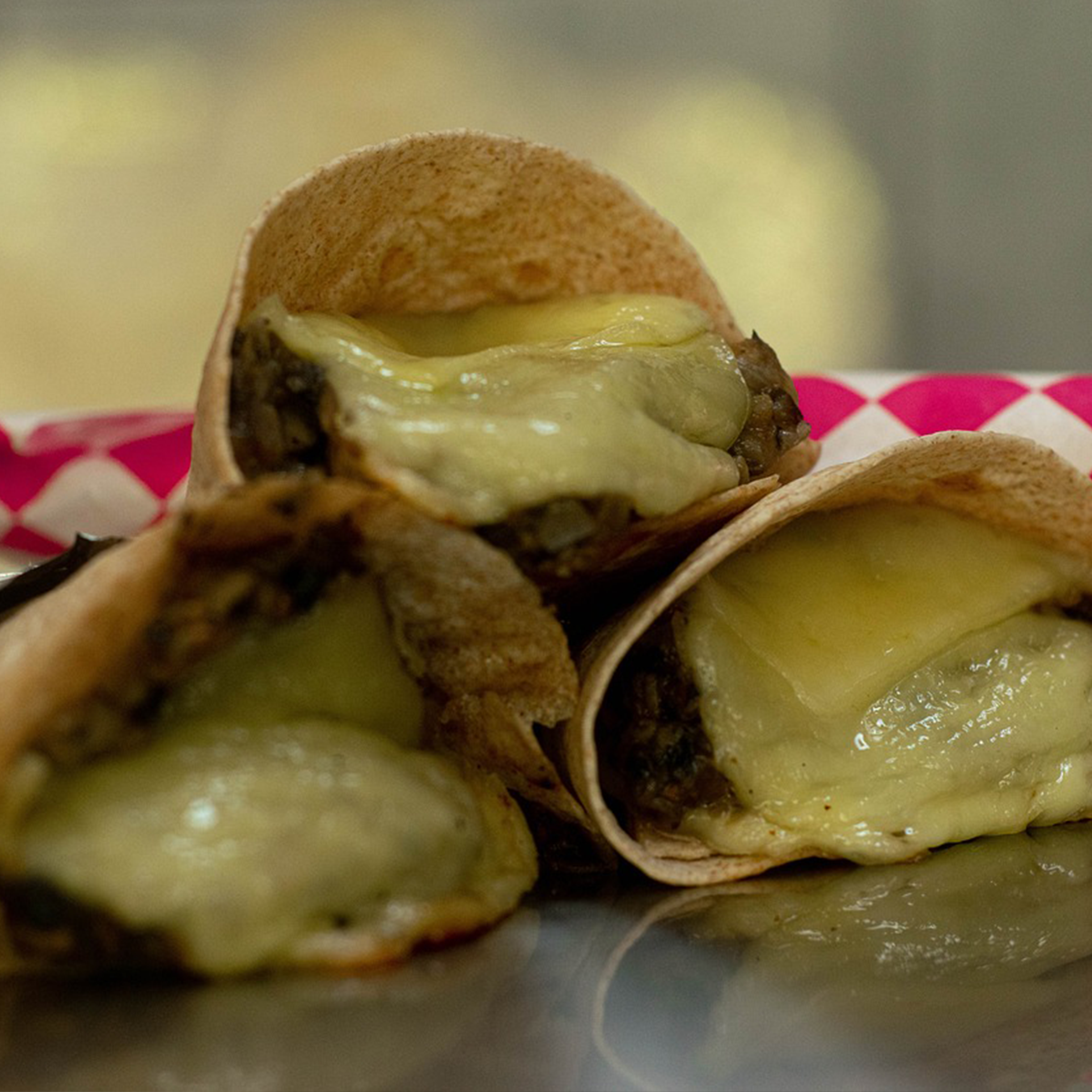 three taquitos oozing with layers of gooey, delicious cheese