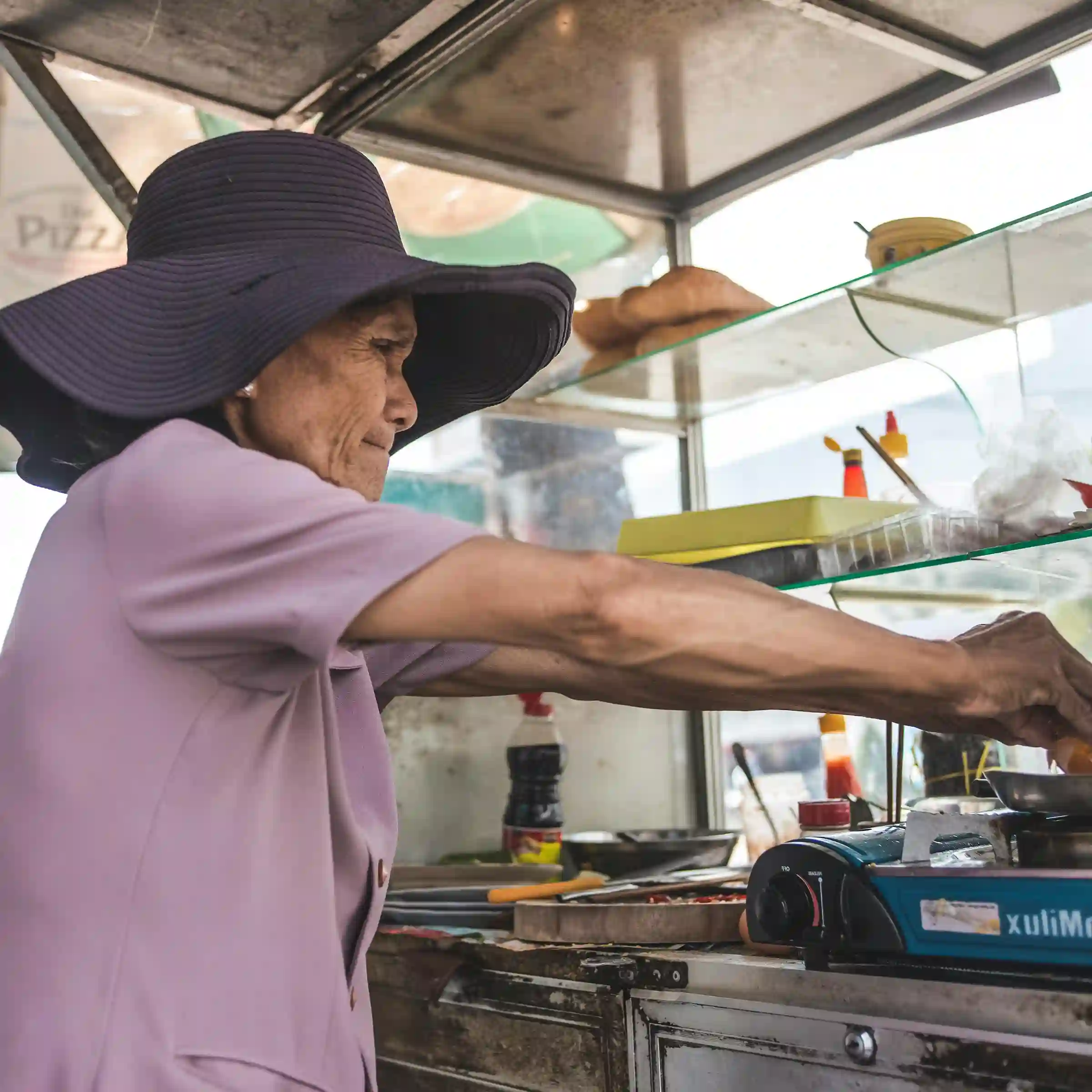 elderly lady cooking in middle of outdoor foodtruck kitchen